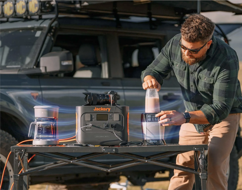 Photographer setting up portable power equipment on a table next to a vehicle during outdoor shoot.