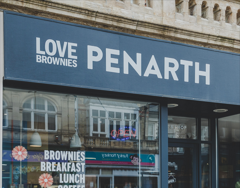 Storefront with blue signage reading "Love Brownies Penarth" displaying breakfast and lunch offerings.