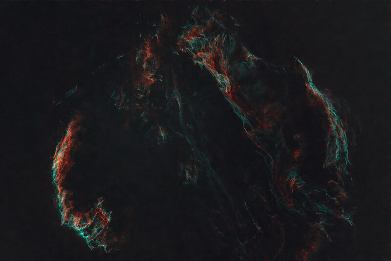 Nebula-like structure with bright orange and cyan strands against dark background.