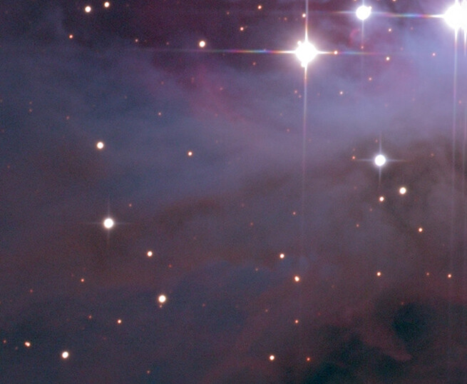 Deep space nebula with scattered stars and bright diffraction spikes across dark purple and blue cosmic gas clouds.