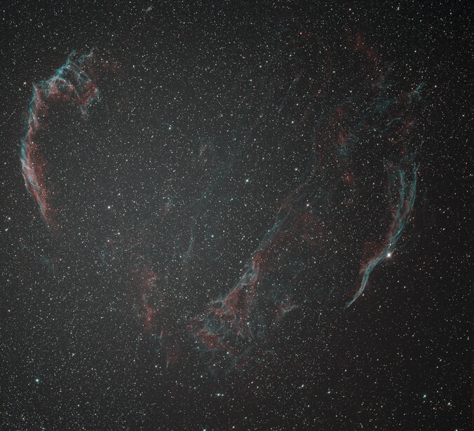 Veil Nebula supernova remnant captured with deep-sky imaging showing wispy red and blue filaments against starfield.
