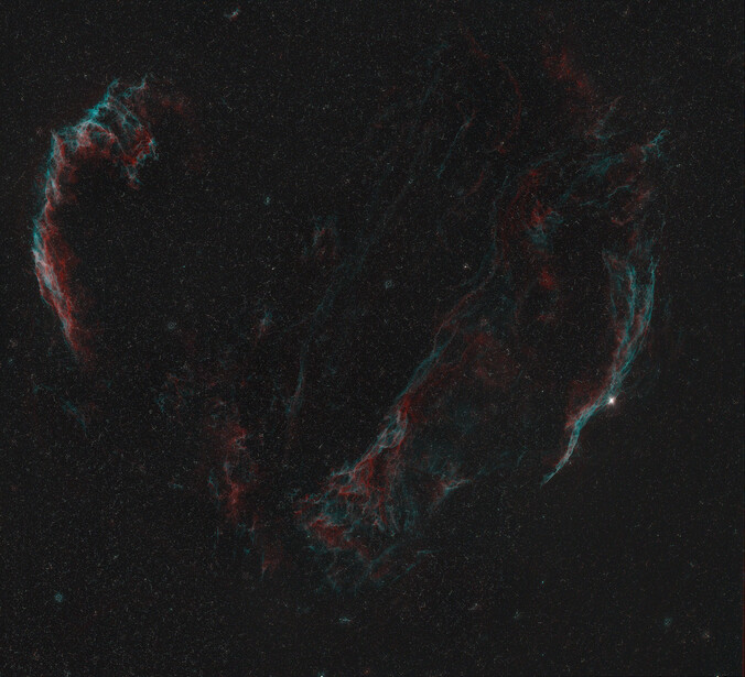 Cygnus Loop nebula filaments in red and cyan against dark starfield.