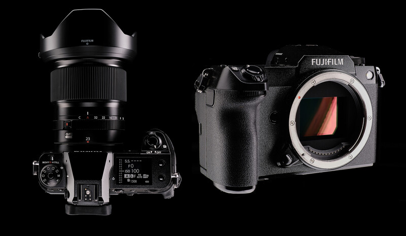 Fujifilm mirrorless camera body and telephoto lens displayed against black background.