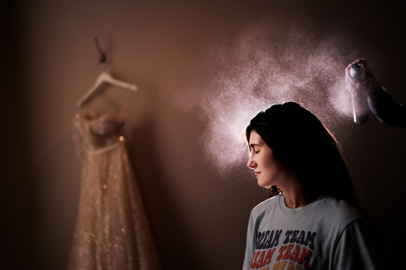 Young woman in profile gazes at suspended figures dissolving into powder against warm, atmospheric lighting.