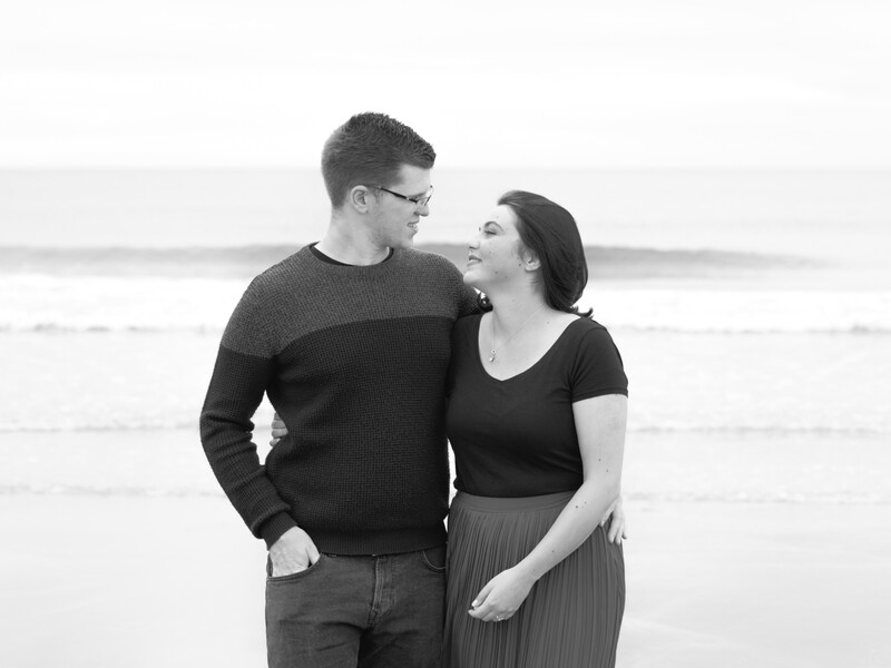 Couple embracing and looking at each other on a beach in black and white.