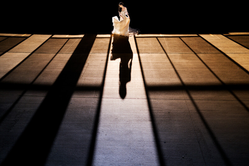 Person running down a sunlit corridor with strong linear shadows cast across the floor.