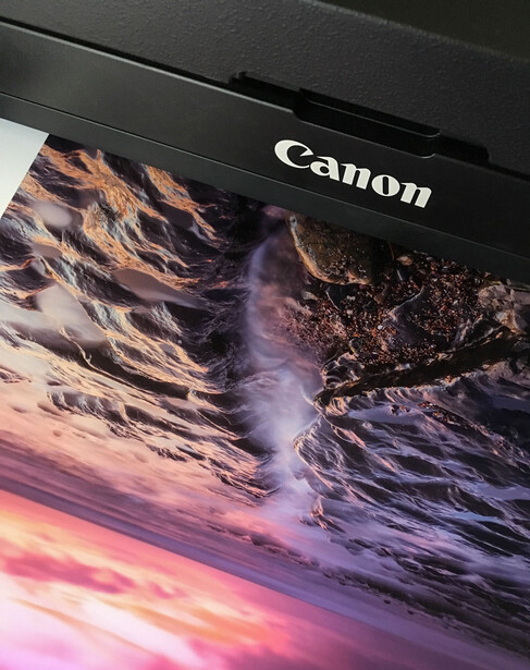 Canon monitor displaying a dramatic landscape photograph with purple and pink tones in the sky and rocky terrain.