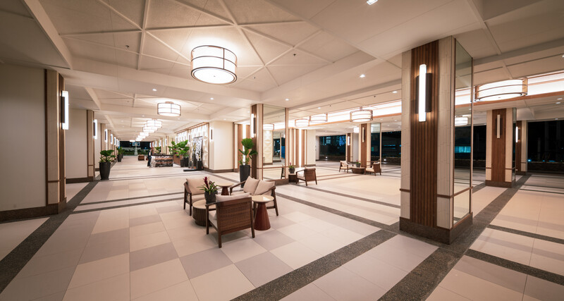 Modern commercial lobby with symmetrical architecture, recessed ceiling lights, and floor-to-ceiling windows at night.