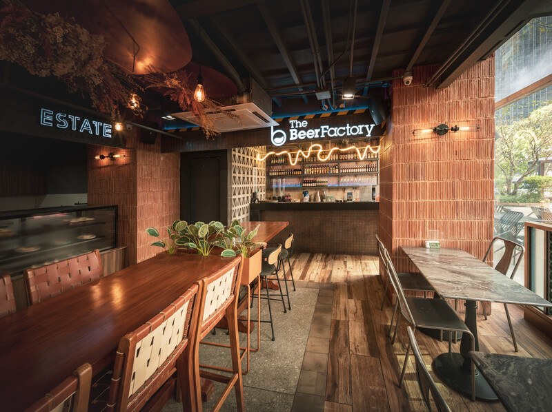 Interior of a modern craft beverage establishment with exposed brick, wood seating, and neon signage.