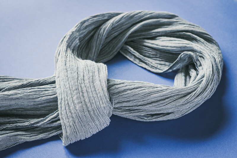 Frayed strands of gray and white twisted rope or fiber bundle tied in a knot against blue background.