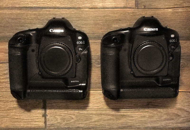 Two Canon EOS-1D X Mark II camera bodies positioned side by side on a wooden surface.