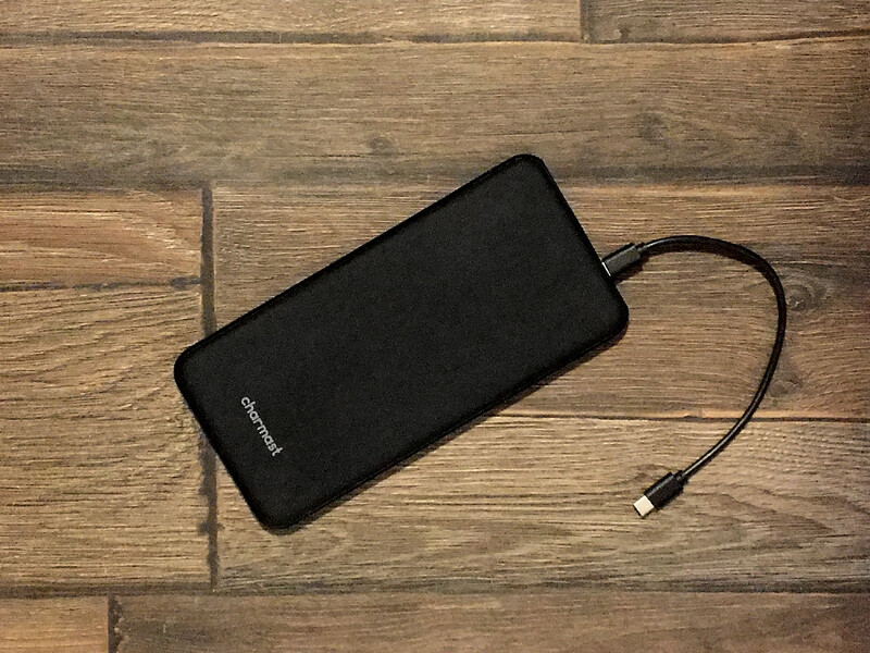 Black portable battery pack with charging cable on wooden surface.