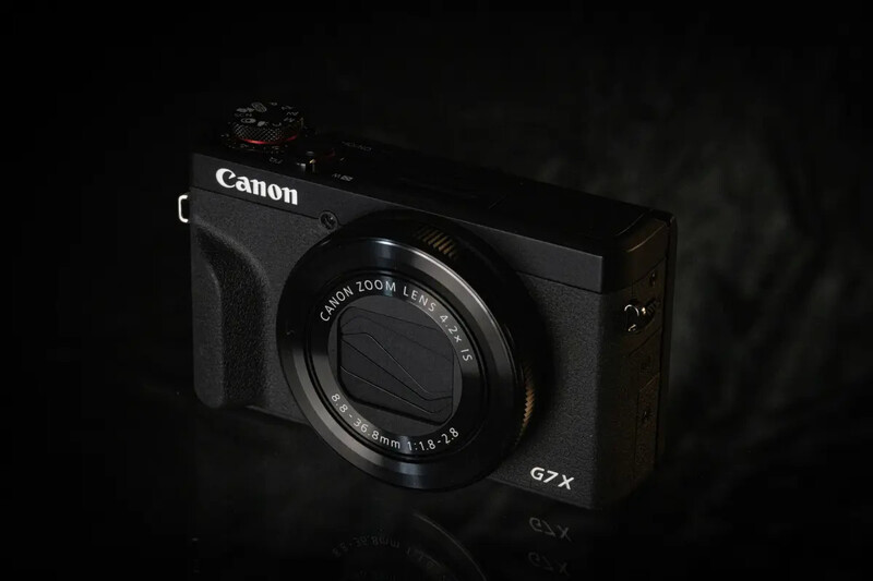 Canon PowerShot G7X compact camera photographed against a dark background.