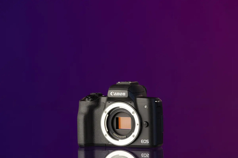 Canon EOS mirrorless camera body displayed against a purple gradient background.
