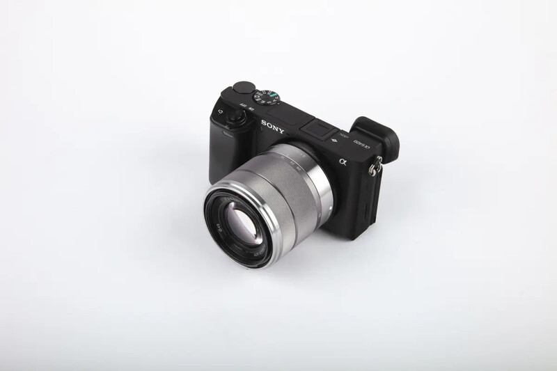 Sony mirrorless camera with silver-toned telephoto lens mounted on white background.