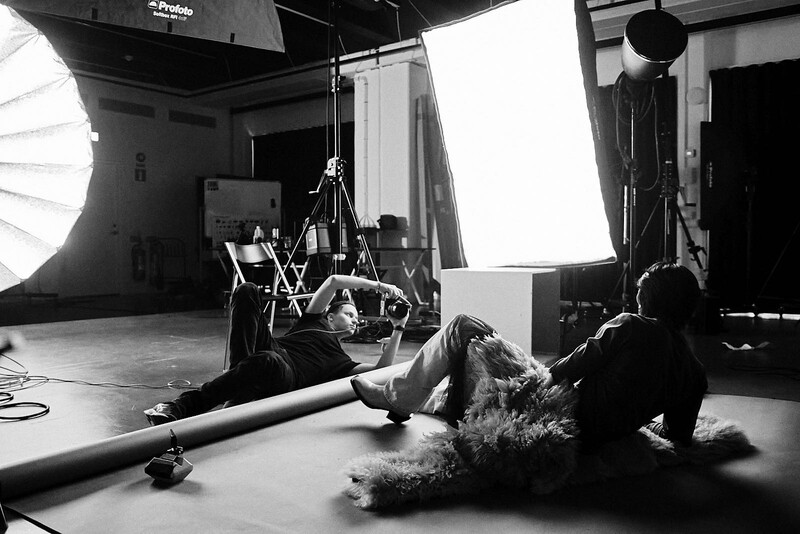 Professional studio setup with musician playing wind instrument positioned low near large soft box lighting.