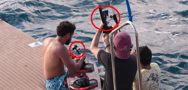 Photographers on a boat deck testing underwater camera housings over ocean water.