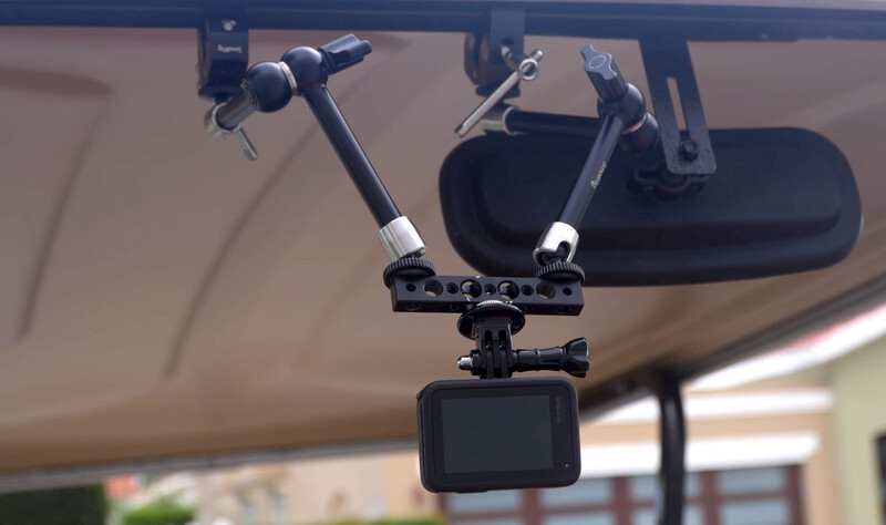 Dashboard-mounted camera rig with dual microphone arms and a smartphone recording device on a vehicle windshield.