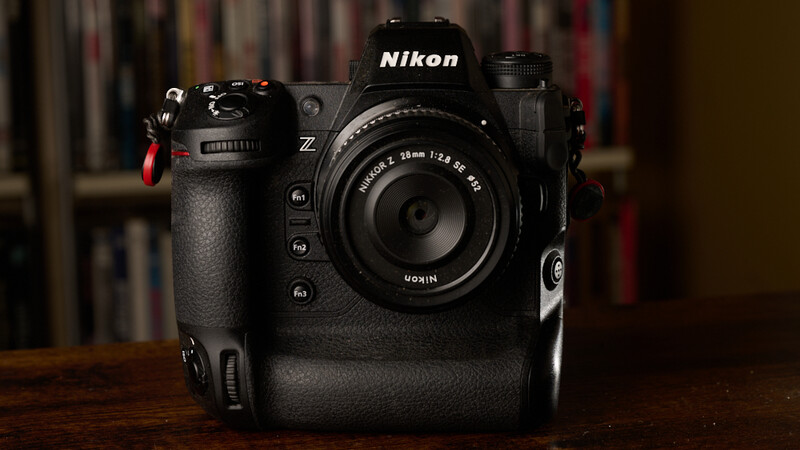 Nikon Z mirrorless camera with battery grip and standard zoom lens on wooden surface.