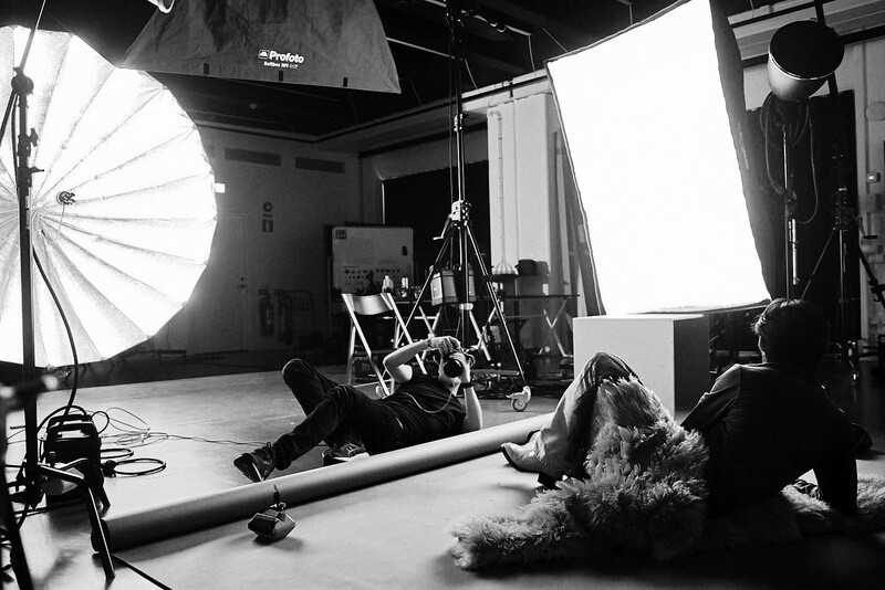 Professional studio setup with large softbox and key light illuminating a seated figure during a black and white photo shoot.