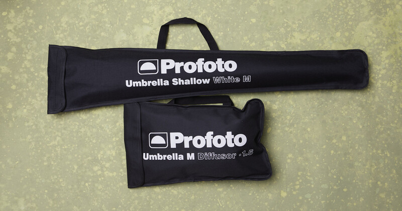 Two black Profoto umbrella carry cases displayed on a textured neutral background.