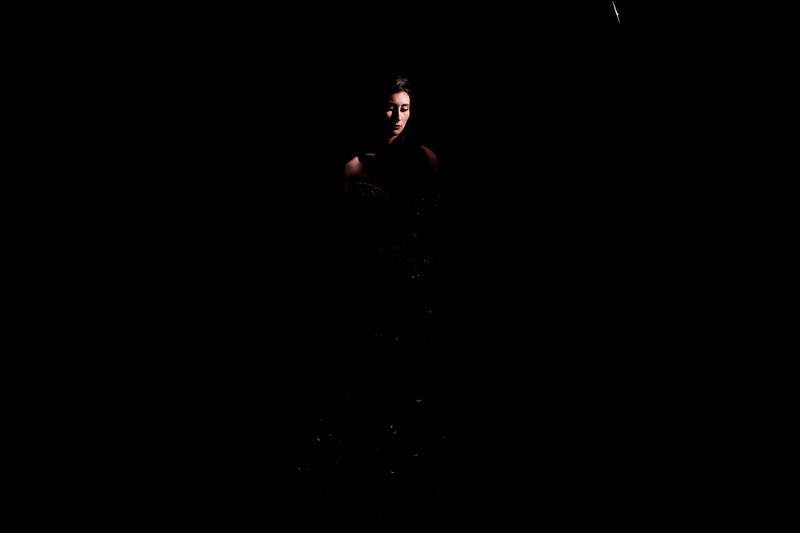 Person illuminated by warm light against a dark background during a portrait session.