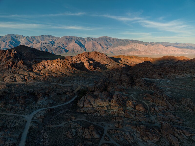 Winding river cutting through layered desert canyon formations at golden hour.