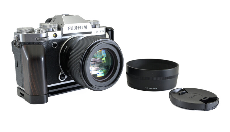 Fujifilm GFX medium format camera with lens, lens hood, and rear cap arranged on white background.