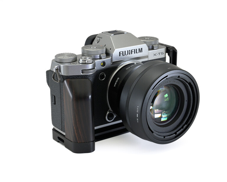 Fujifilm mirrorless camera with silver top plate and black body, paired with a standard zoom lens on a white background.