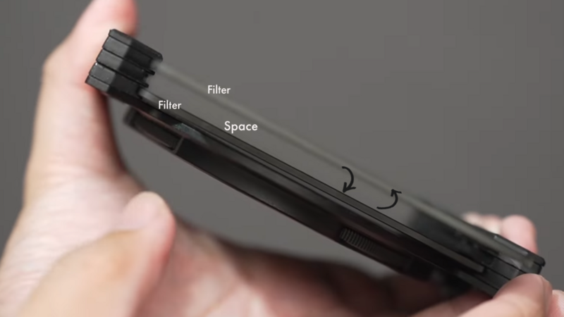 Hand holding a black camera filter with labeled components including filler sections and a space area.