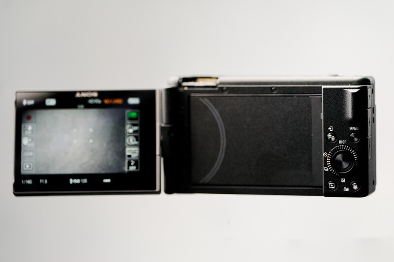 Two compact digital cameras displayed side by side, showing front and back views with LCD screens and control dials visible.