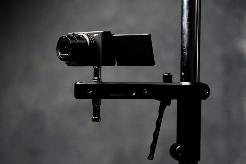 Sony camera mounted on a black gimbal stabilizer rig against a gray backdrop.