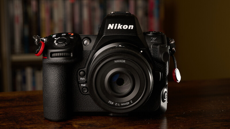 Nikon Z9 full-frame mirrorless camera with 24-70mm lens on wooden table, equipped with red wrist strap and accessories.