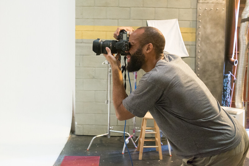 Photographer shooting in a studio setup with professional lighting and white backdrop.