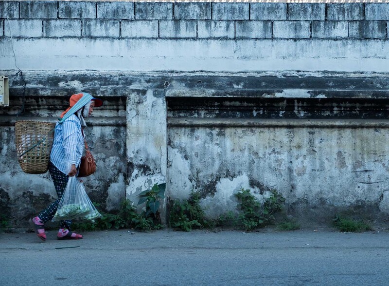 A market stall worker walks past a wall in Chiang Mai, Thailand