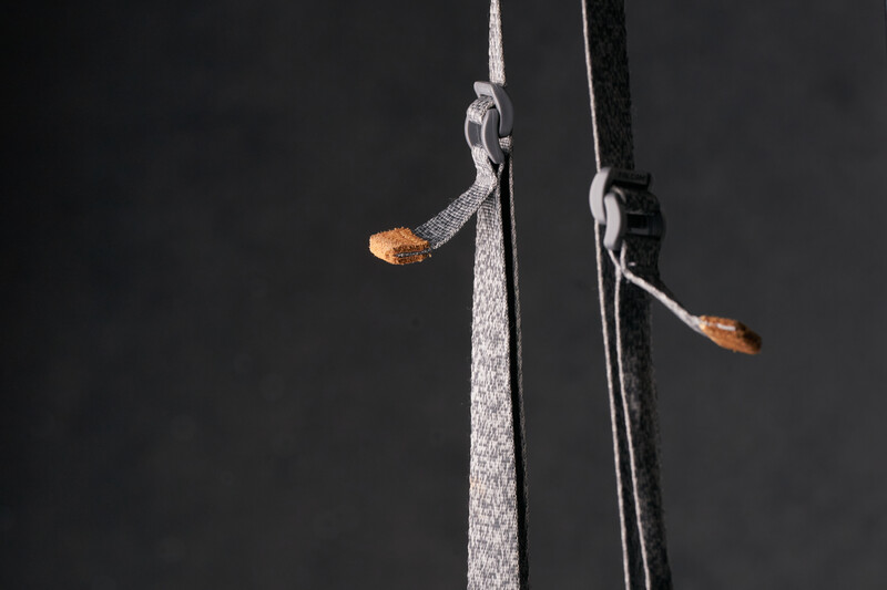 Two delicate insects suspended on thin threads against a dark background.