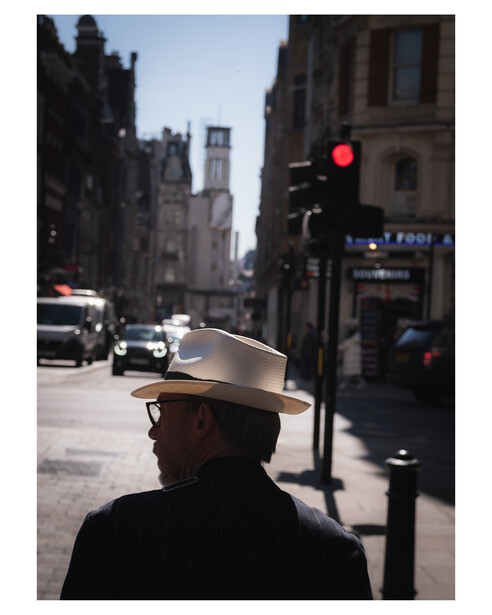 A man wearing a hat walks in the sunshine during an early spring day in London