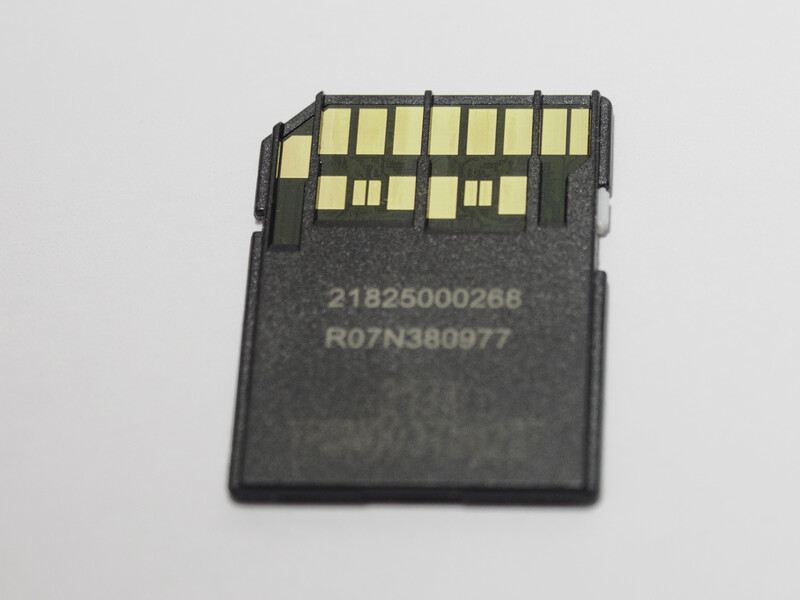 Memory card shown from front and back, displaying gold contact pins and printed identification numbers.