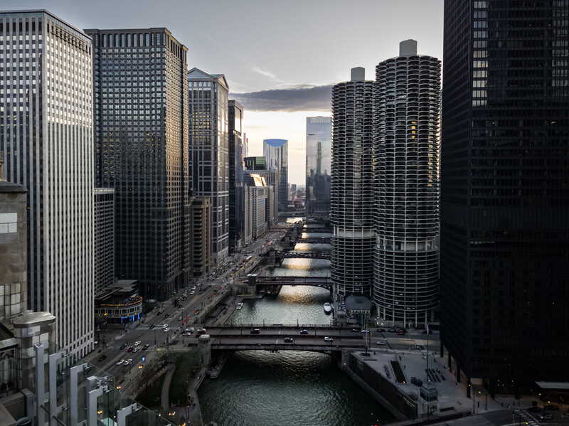 Downtown cityscape with Chicago River flowing between tall buildings at dusk.