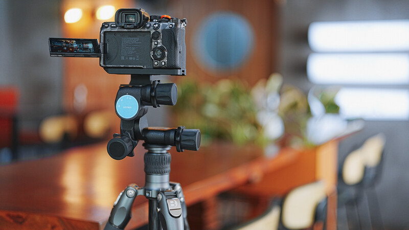 Mirrorless camera mounted on a tripod with articulating arm and ball head in an indoor studio setting.