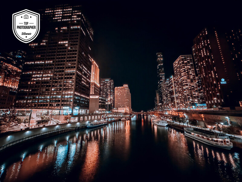 Urban night scene of illuminated skyscrapers reflected in a calm river or canal.