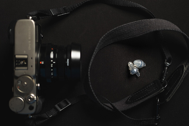 Professional camera gear arranged on black fabric, including a film SLR body, lens, and camera bag with accessories.