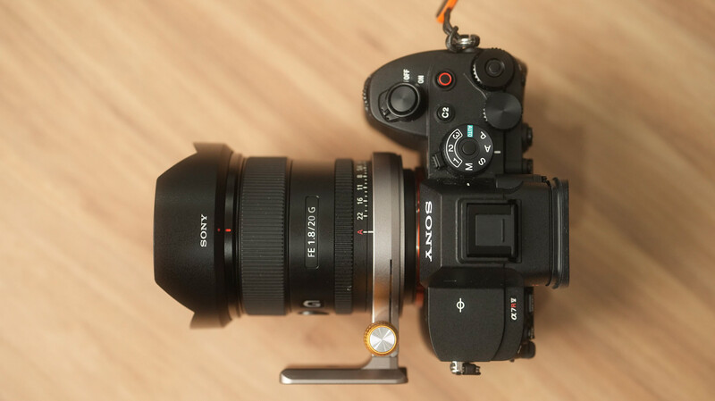 Sony mirrorless camera with wide-angle lens and external microphone mounted on wooden surface.