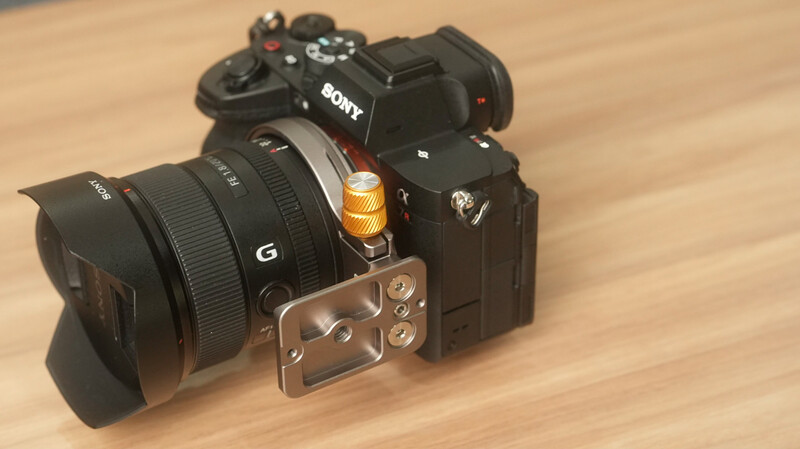 Sony mirrorless camera with Sony G-series lens and metal L-bracket mounted on wooden surface.