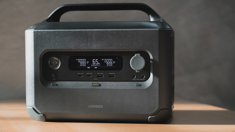 Ugreen portable power station with digital display showing power metrics and dual control knobs.