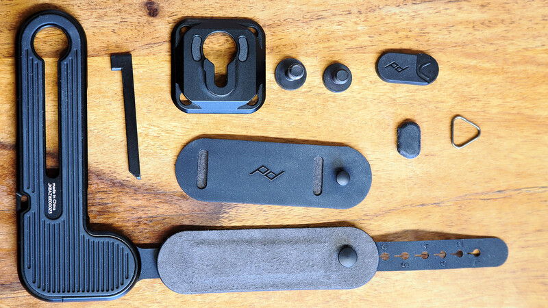 Flat lay of camera strap and mount accessories arranged on wooden surface.