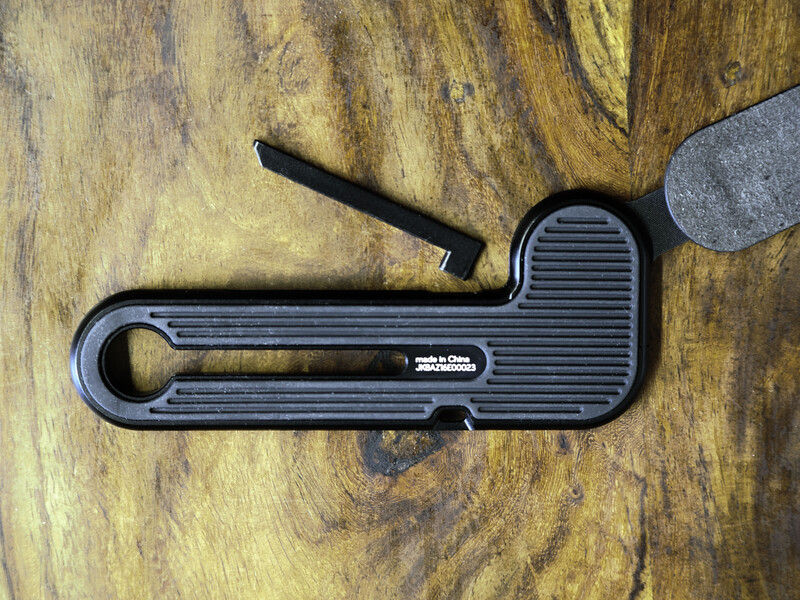 Black ball head wrench with hex key attachment on wooden surface.