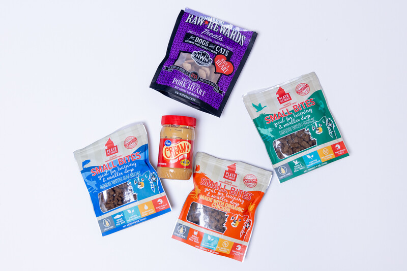 Five packaged food products arranged on a white background, including peanut butter, cereal, and grain-based items.