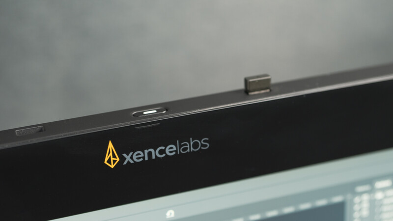 Top bezel of a Xence Labs monitor displaying the brand logo and built-in webcam.
