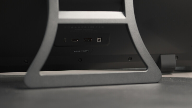 Close-up of a white curved monitor stand base showing ports and connectivity options on the back panel.